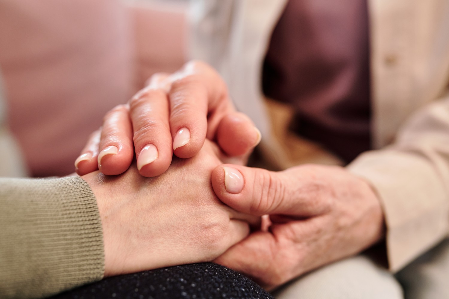 Close-up of a caregiver gently holding the hands of an elderly person, expressing warmth and support