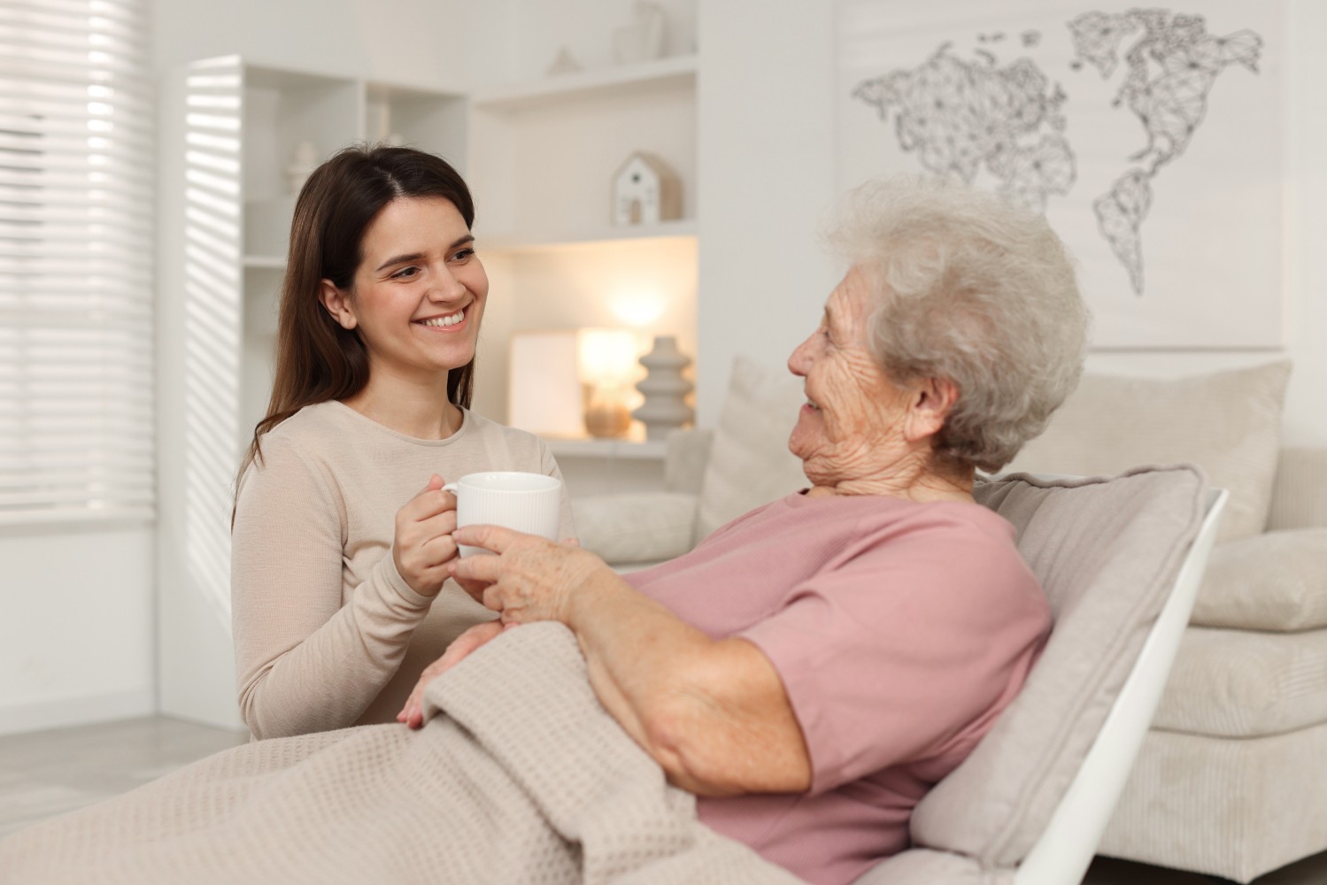 A smiling female caregiver visiting a senior woman at her home